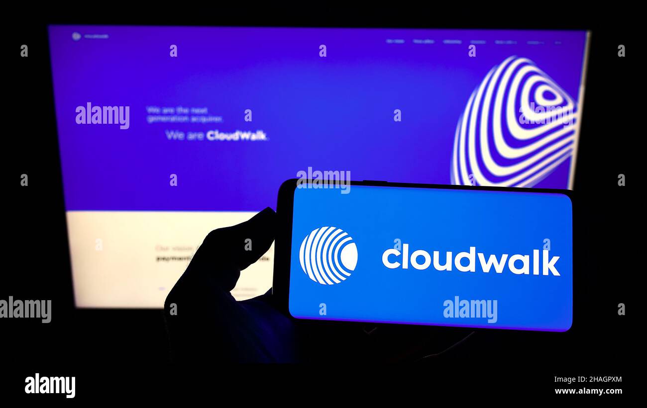 Persona che tiene smartphone con il logo della società di pagamento brasiliana CloudWalk Inc. Sullo schermo di fronte al sito web. Mettere a fuoco sul display del telefono. Foto Stock