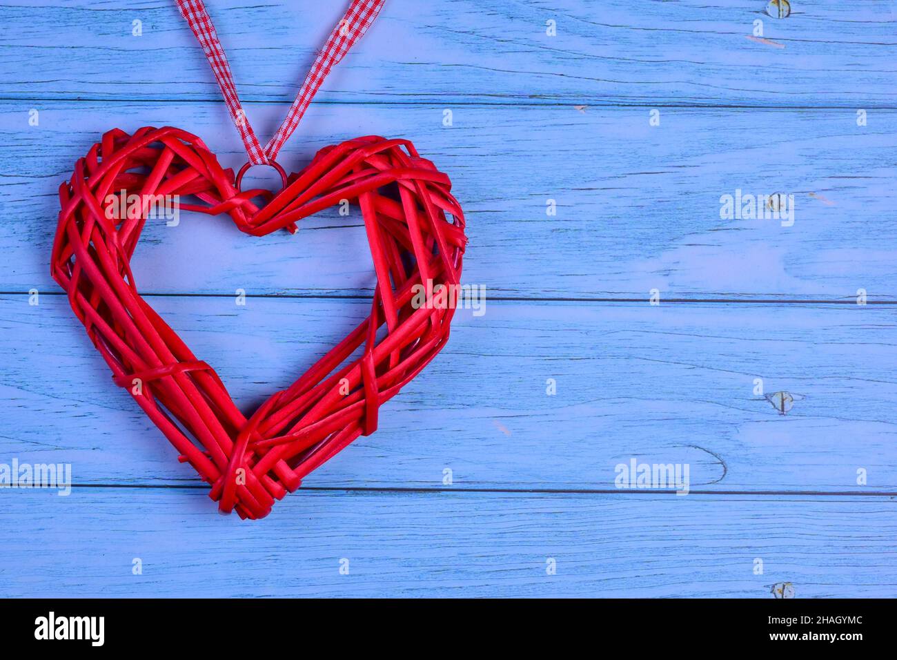 Su uno sfondo di legno di tavole blu orizzontali a sinistra, c'è un cuore rosso decorativo. Sulla destra c'è un posto per iscrizioni per diversi Foto Stock
