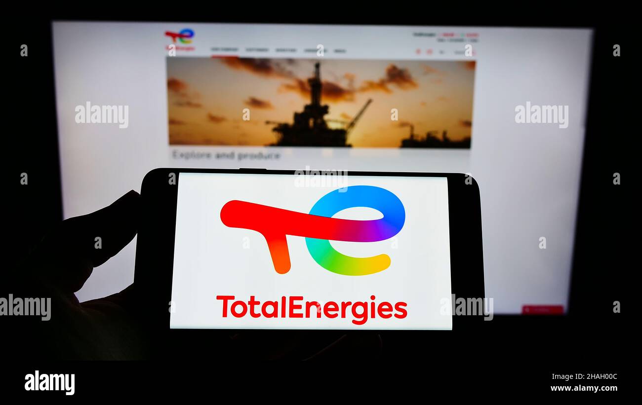 Persona che detiene il cellulare con il logo della società francese di petrolio e gas TotalEnergies se sullo schermo di fronte al sito web aziendale. Mettere a fuoco sul display del telefono. Foto Stock