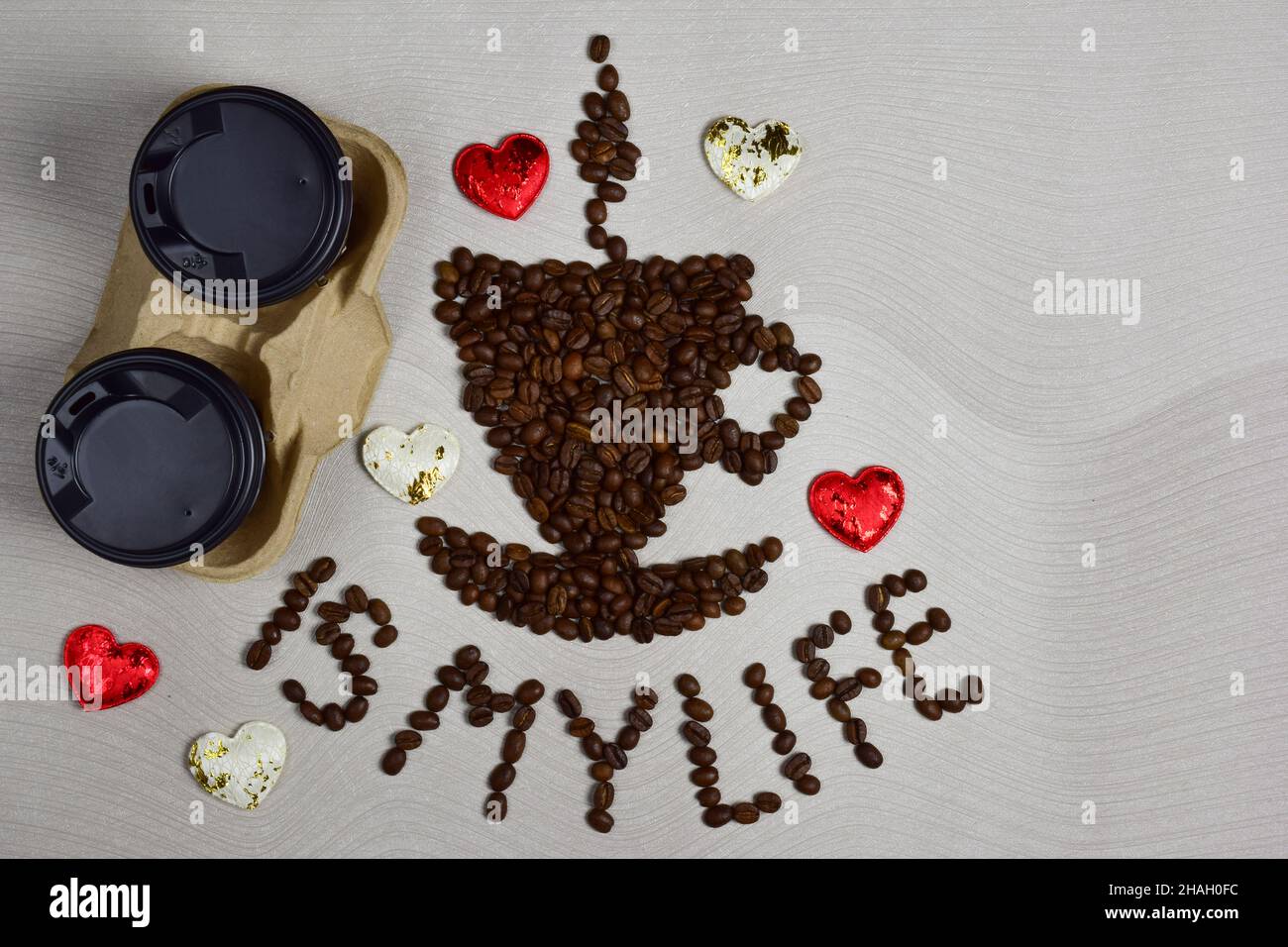 Questa figurina sotto forma di una tazza di caffè con un piattino è fatta di chicchi di caffè con l'iscrizione CAFFÈ È LA MIA VITA sotto di esso. Sulla sinistra ci sono tw Foto Stock