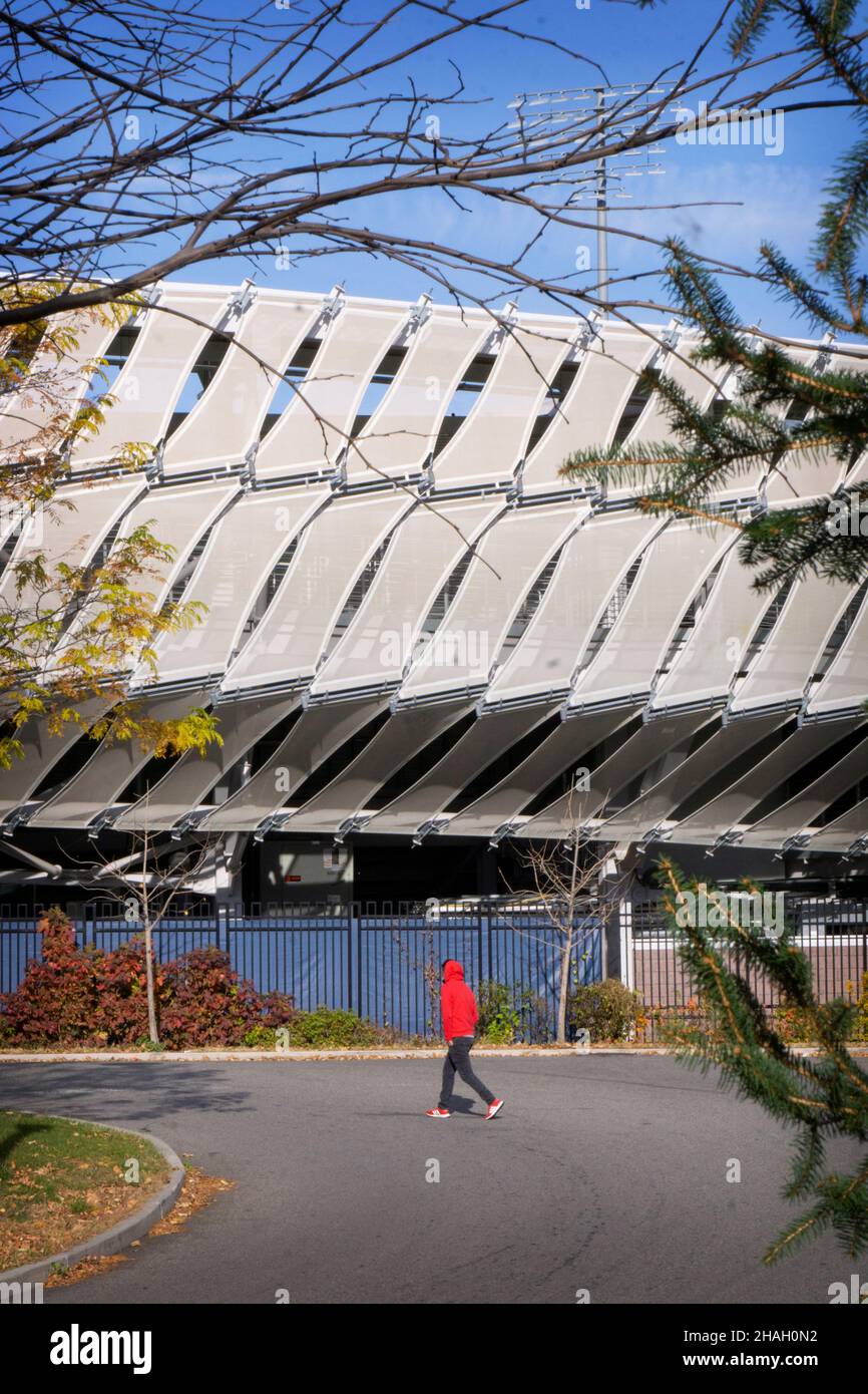 Un uomo in una felpa rossa cammina accanto al Grandstand Stadium presso il USTA Billie jean King National Tennis Center nel Flushing Meadows Corona Park di Queens, New York. Foto Stock