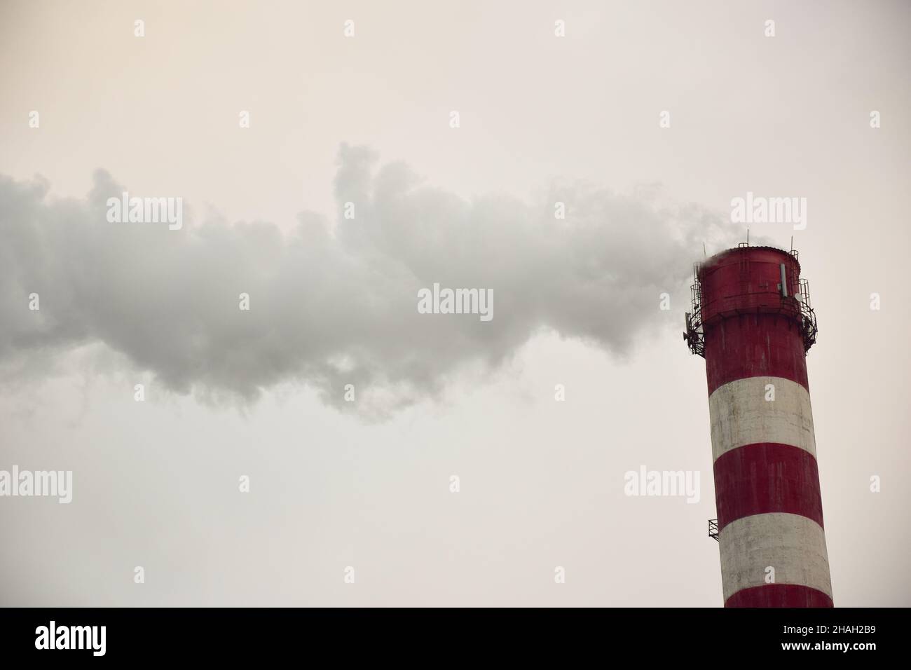 Fumante camino a strisce di una pianta o di una fabbrica su uno sfondo cielo Foto Stock