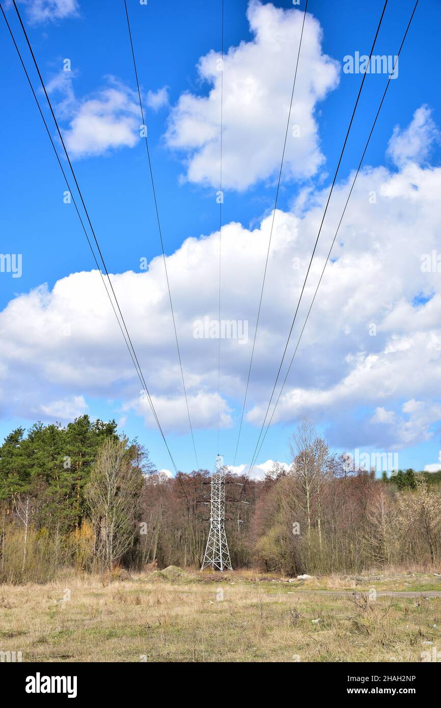 Linea di alimentazione ad alta tensione da cui i cavi lunghi vanno nel futuro sullo sfondo di un cielo luminoso con nuvole bianche Foto Stock