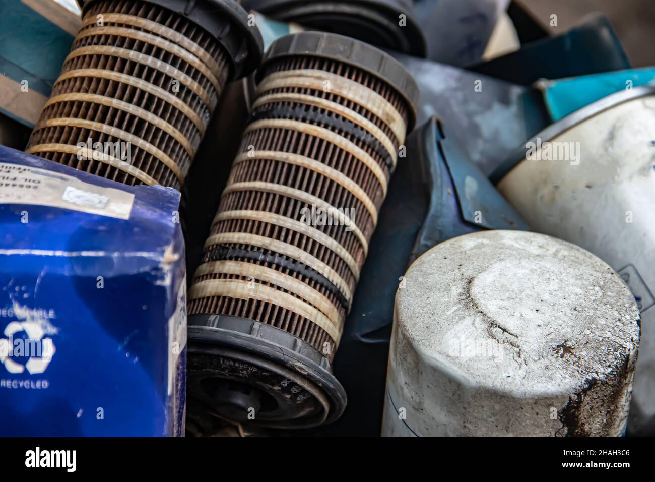 Cumulo di vecchi filtri olio usati oleosi in officina meccanica, pronti per il riciclaggio Foto Stock