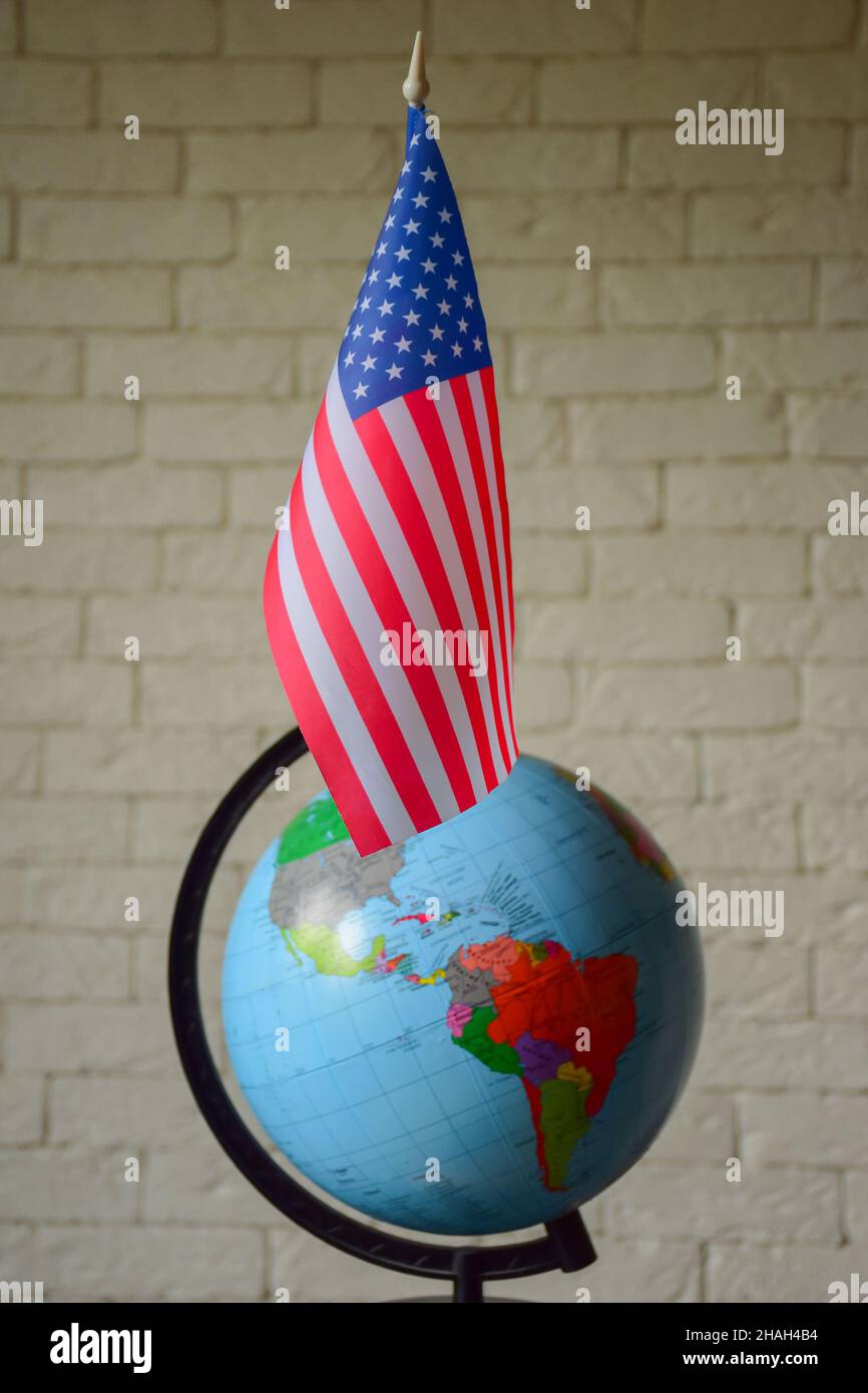 La bandiera degli Stati Uniti è contro un mondo sfocato con contorni oscuri e un muro di mattoni. Sfondo sfocato Foto Stock