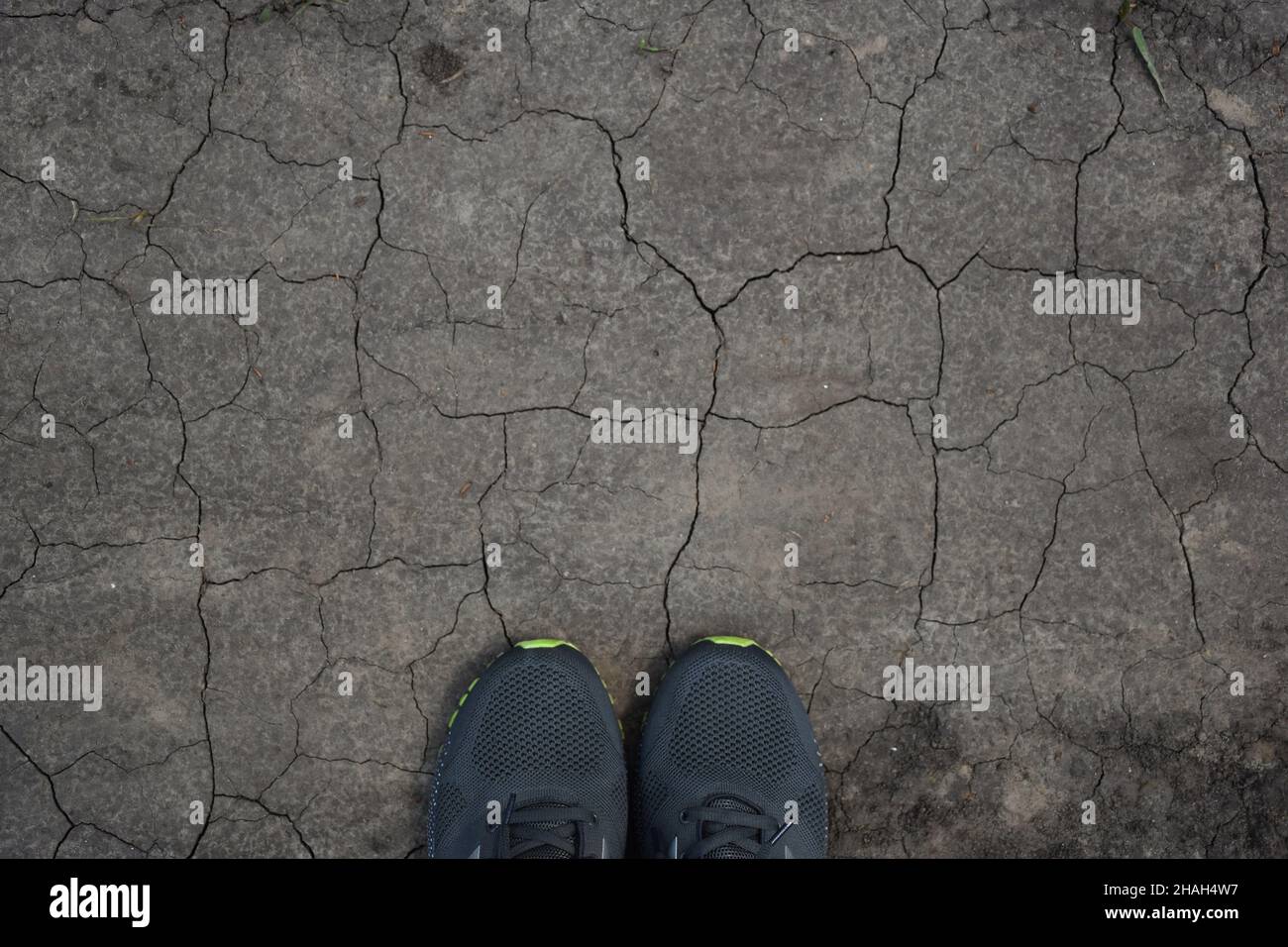 Su un terreno arido, incrinato ovunque nella parte inferiore del telaio, due sneakers sbirciano fuori. C'è molto spazio nella parte superiore per inserire una scritta Foto Stock