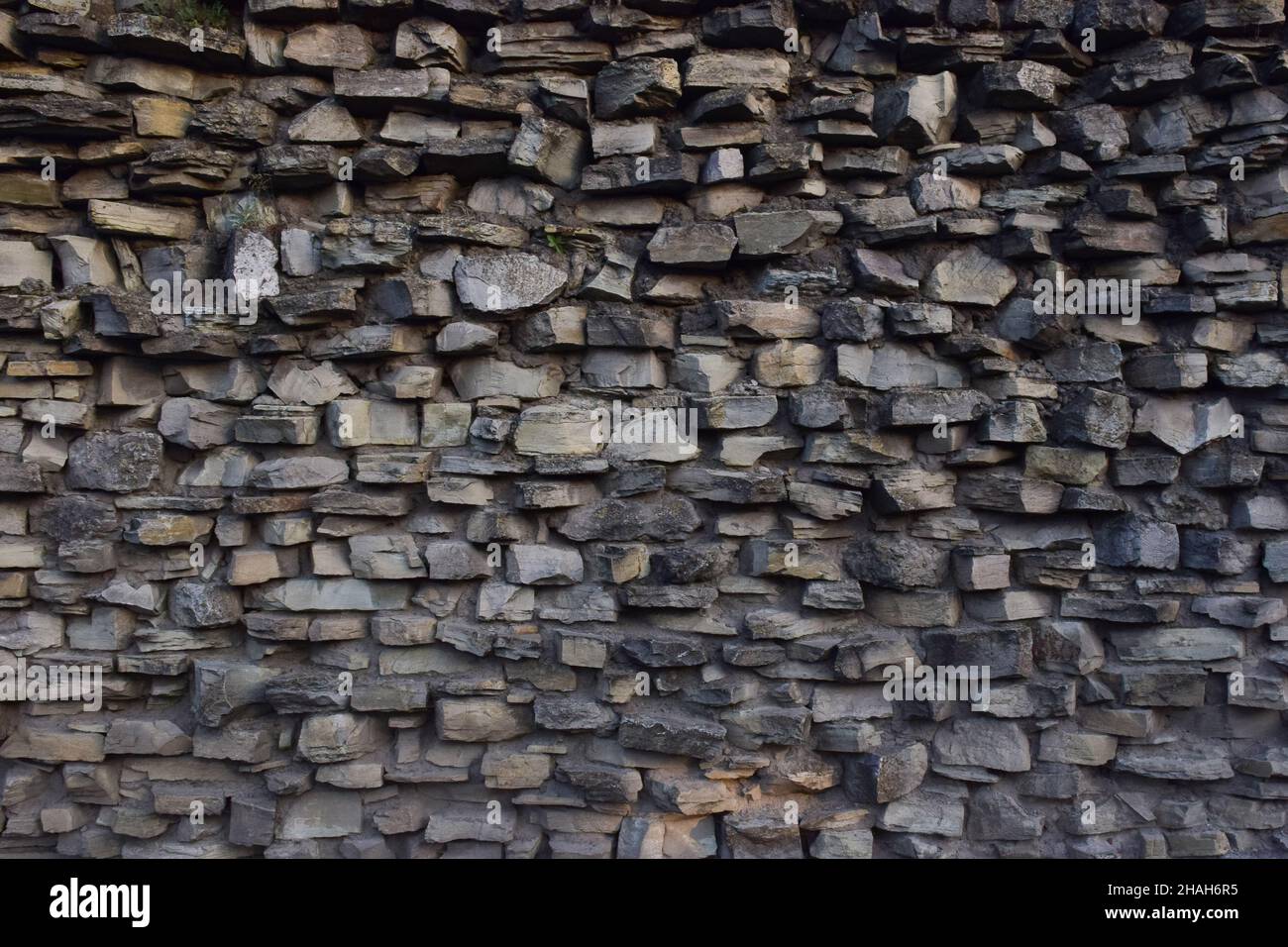 Parete in granito grigio pietra rinforzata con cemento per tutta la struttura di pietre di diverse dimensioni e forme Foto Stock