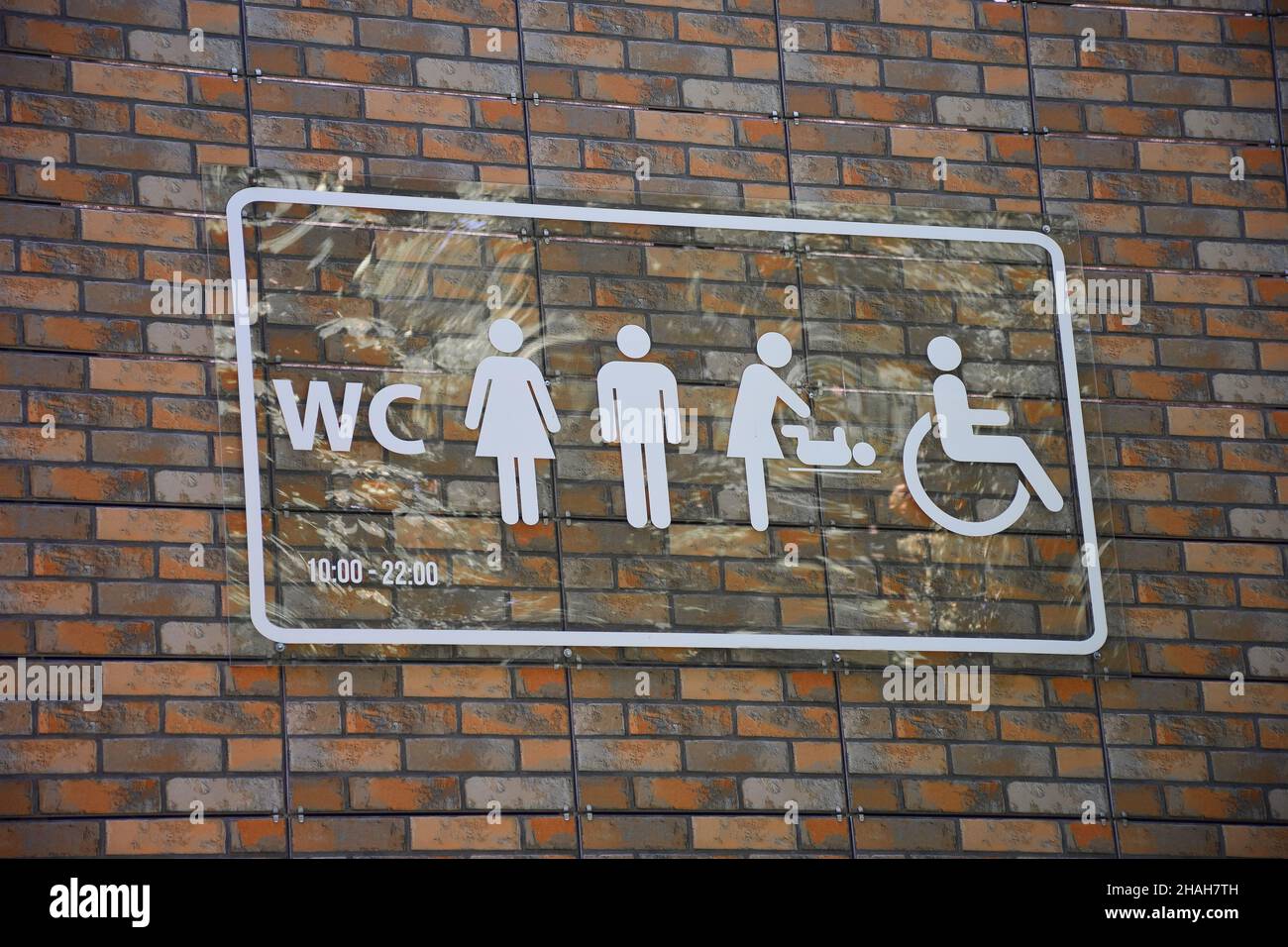 Sul muro di mattoni c'è un cartello con simboli diversi per la designazione del gabinetto Foto Stock
