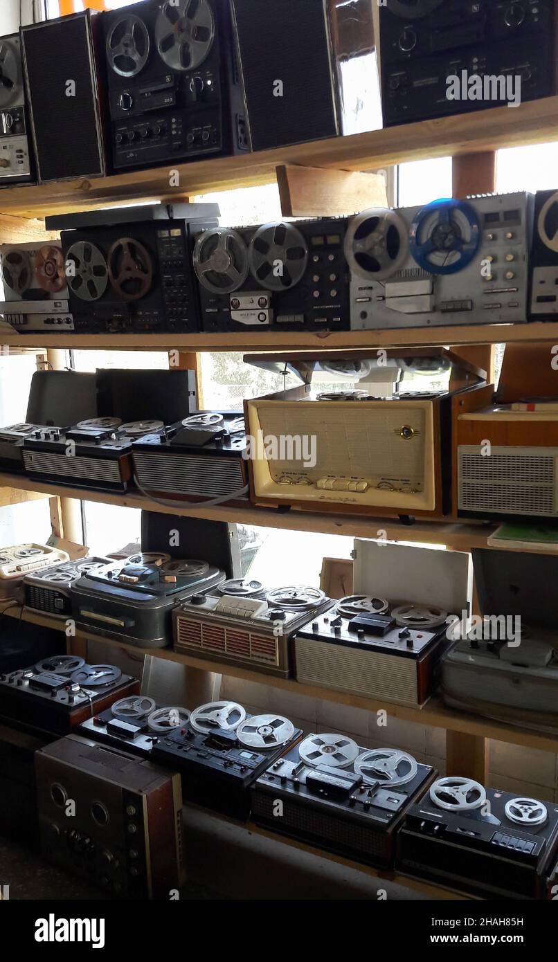 File di vecchi registratori a nastro e radio-nastri in bobina si trovano su scaffali di un negozio o di un'esposizione Foto Stock