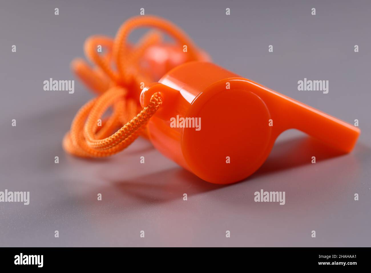 Fischio arancione in plastica con corda su sfondo grigio Foto Stock
