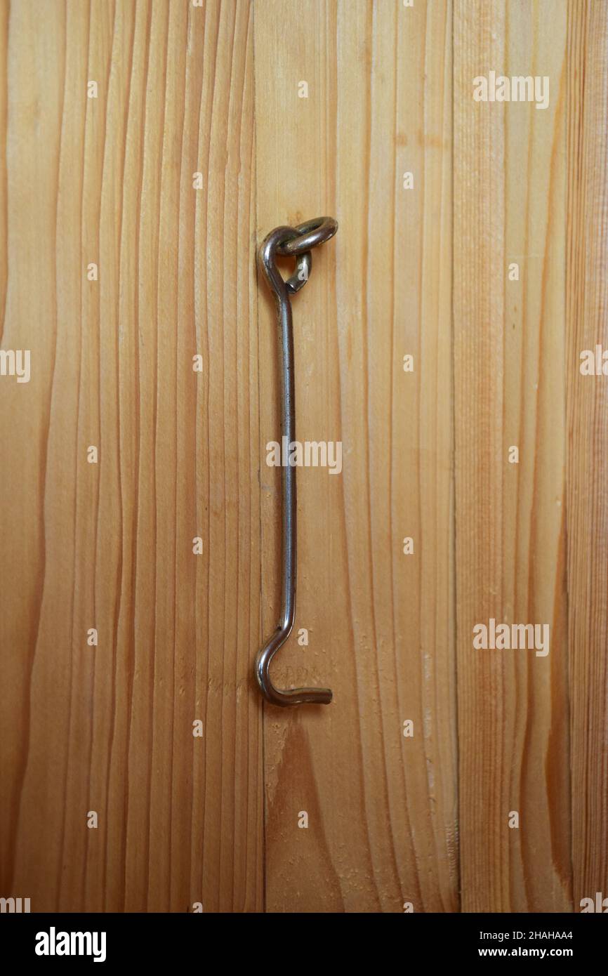Un gancio di ferro si appende sul pannello di legno della porta per chiudere  la porta. La tessitura del legno è chiaramente visibile Foto stock - Alamy
