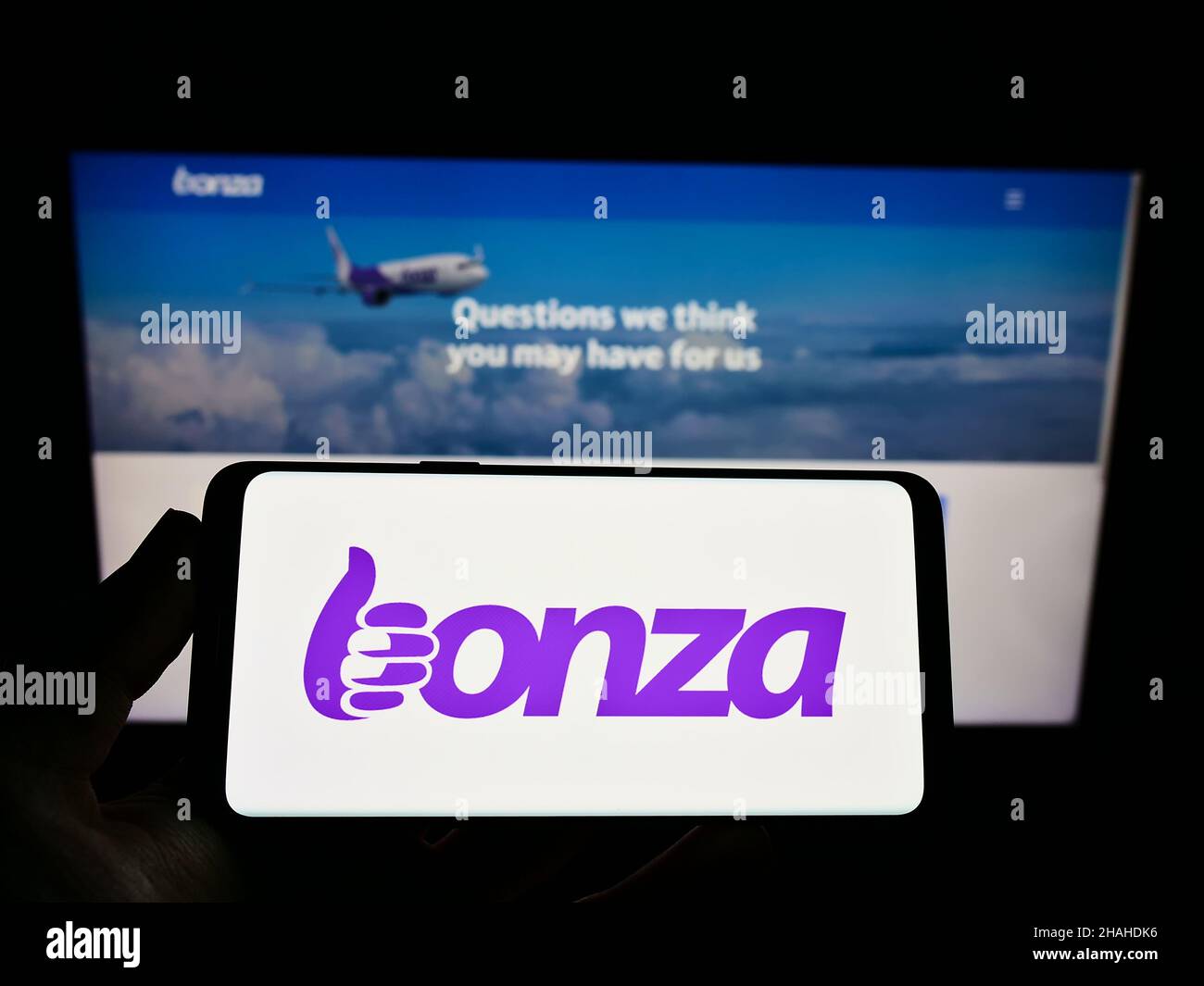 Persona che tiene il cellulare con il logo della compagnia aerea australiana Bonza Aviation Pty Ltd. Sullo schermo di fronte alla pagina web dell'azienda. Mettere a fuoco sul display del telefono. Foto Stock