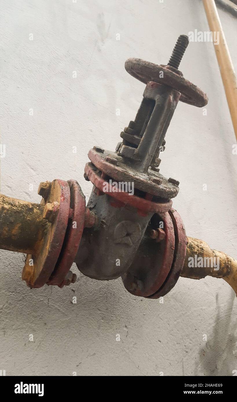 Il vecchio grande rubinetto del gas sul tubo è fotografato da vicino da sotto Foto Stock