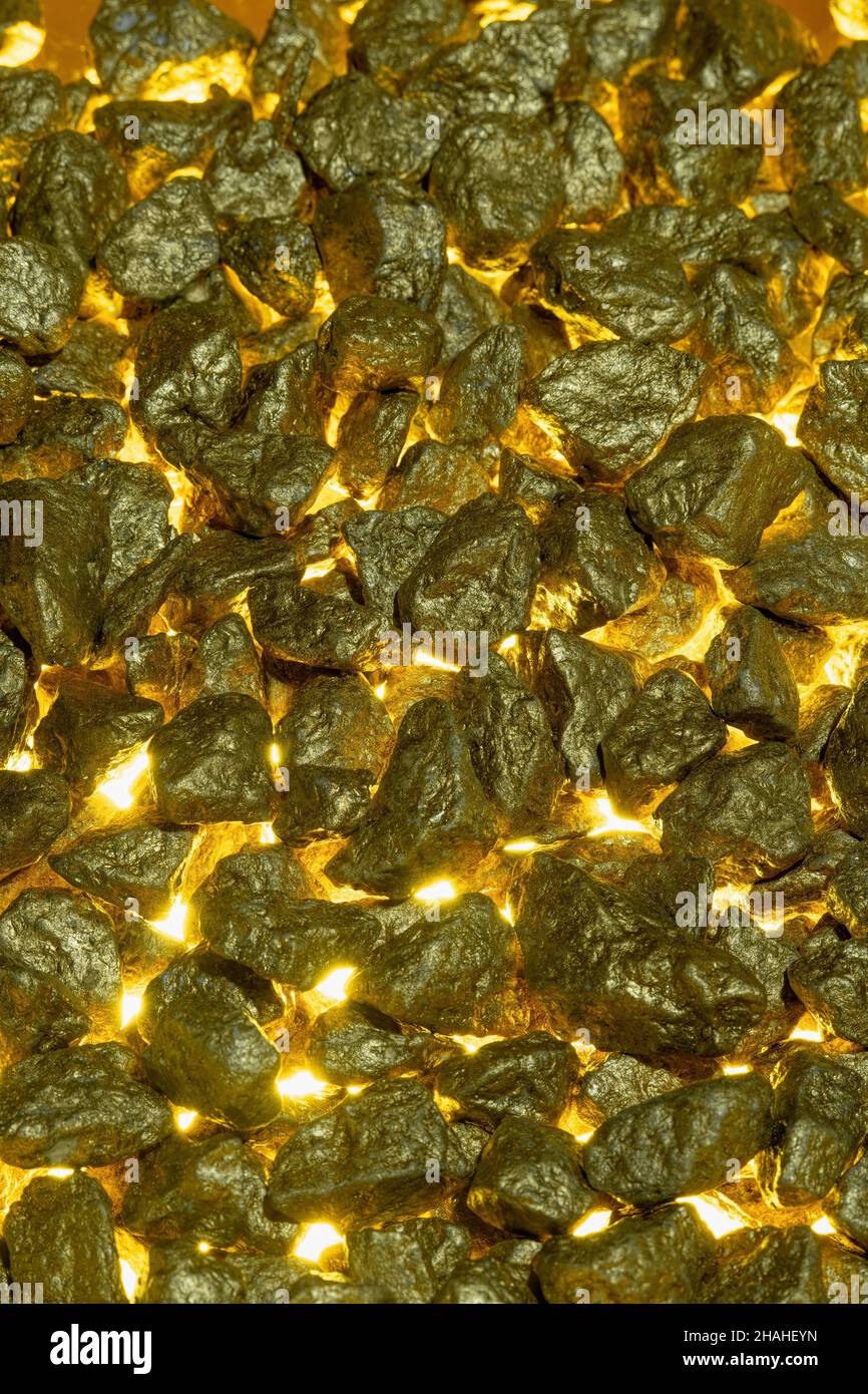 Pepite d'oro come sfondo con luce dorata dal basso. Foto Stock