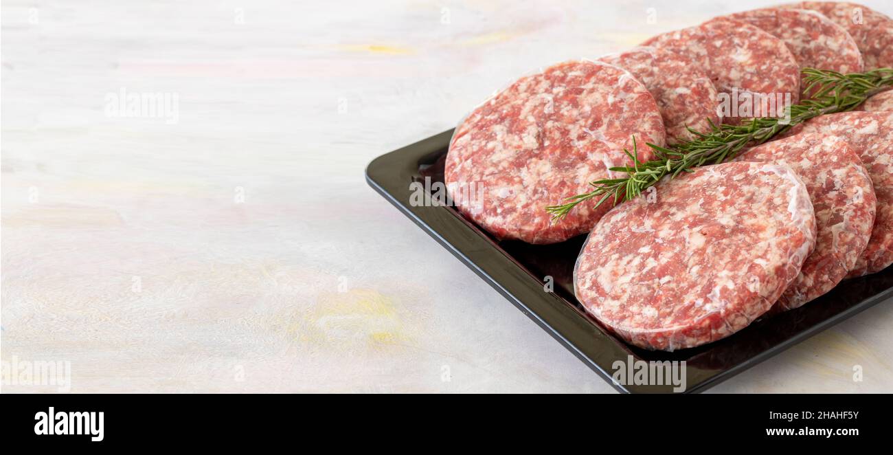 carne di hamburger di manzo crudo confezionata su sfondo di legno bianco. Sfondo di carne. Spazio di copia Foto Stock