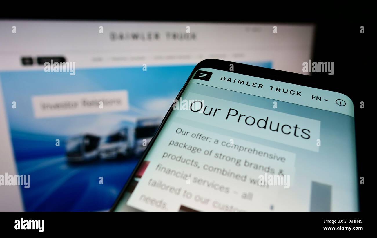 Telefono cellulare con sito web e logo del costruttore tedesco di veicoli commerciali Daimler Truck AG sullo schermo. Mettere a fuoco sulla parte superiore sinistra del display del telefono. Foto Stock