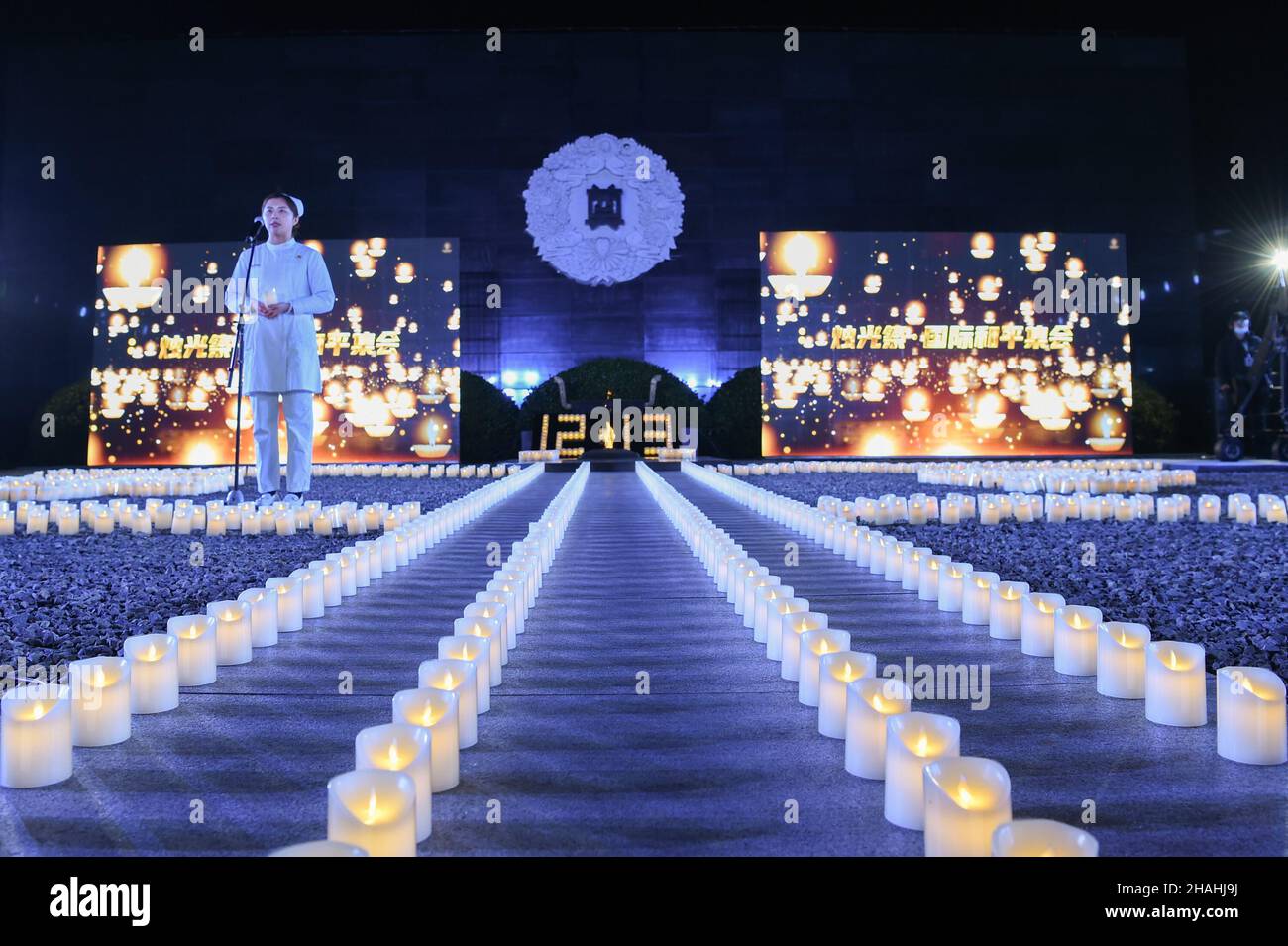 (Un operatore medico parla a una veglia a lume di candela per commemorare le vittime del massacro di Nanjing in occasione dell'ottavo giorno commemorativo nazionale presso la Sala commemorativa delle vittime del massacro di Nanjing da parte degli invasori giapponesi a Nanjing, capitale della provincia di Jiangsu della Cina orientale, 13 dicembre 2021. Il massacro di Nanjing ebbe luogo dopo che le truppe giapponesi catturarono la città il 13 dicembre 1937. Nel corso di sei settimane, hanno ucciso circa 300.000 civili cinesi e soldati disarmati in uno degli episodi più barbarici della seconda guerra mondiale (Xinhua/li Bo) Foto Stock