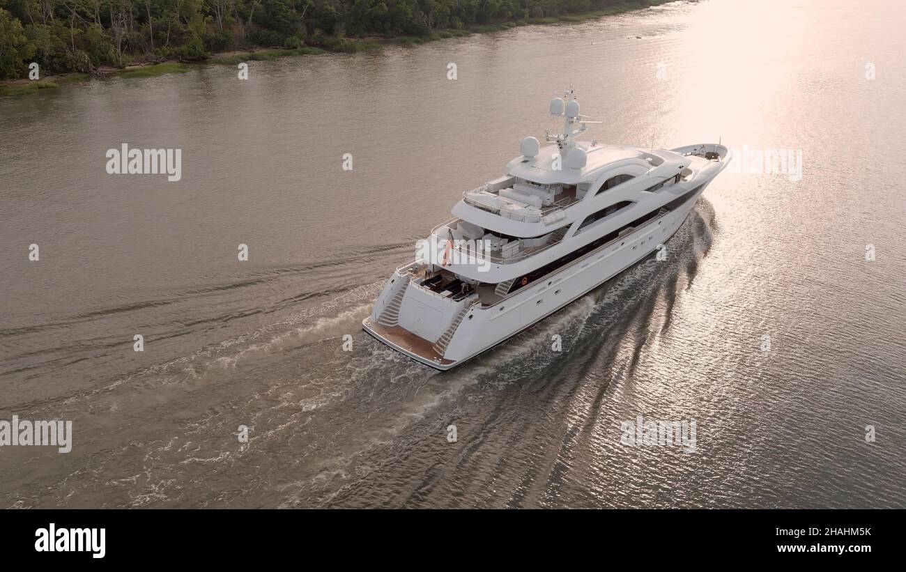 Un grande yacht si muove lungo la costa all'alba. Foto Stock