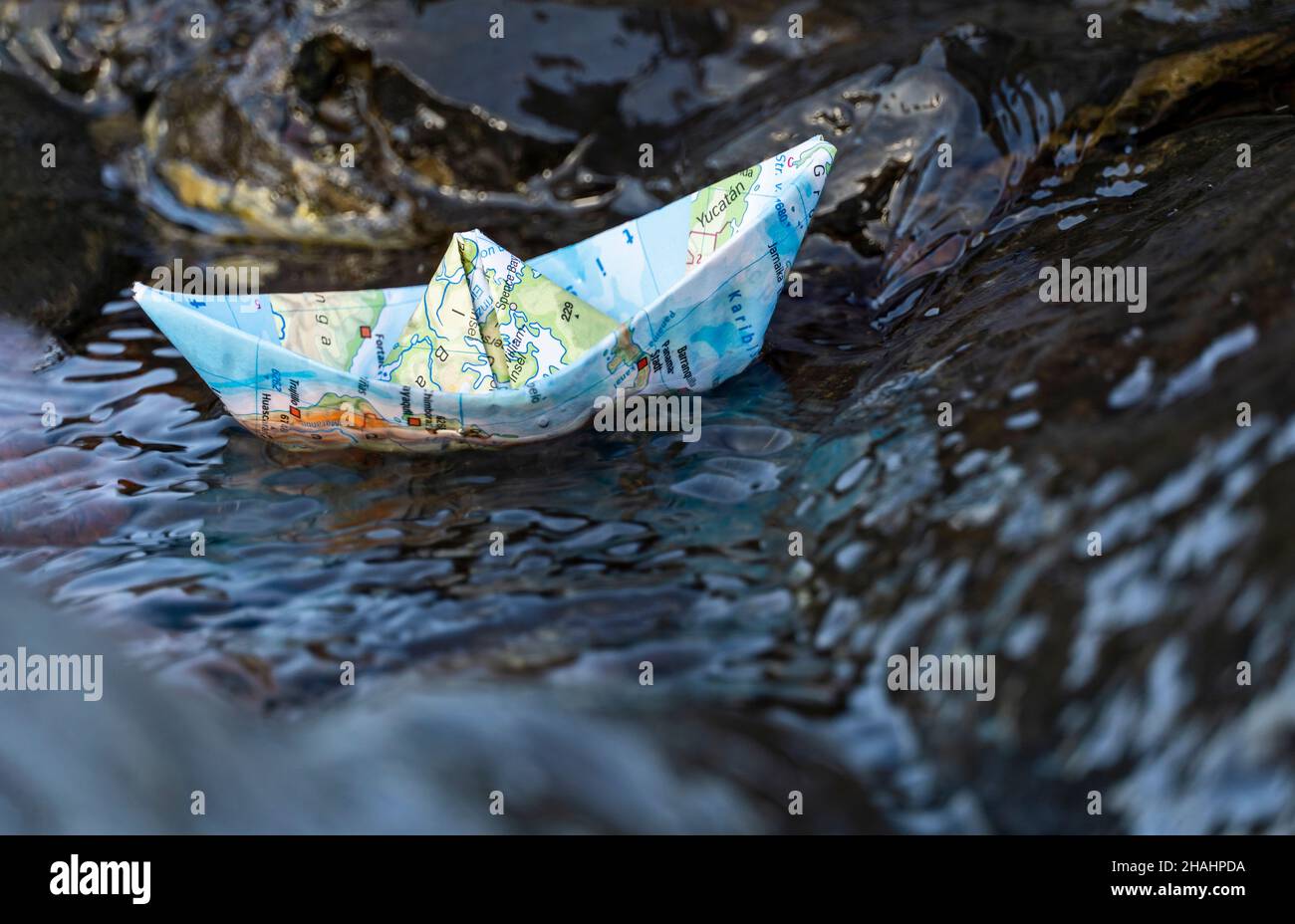 La piccola nave di carta galleggia in acqua disturbata Foto Stock