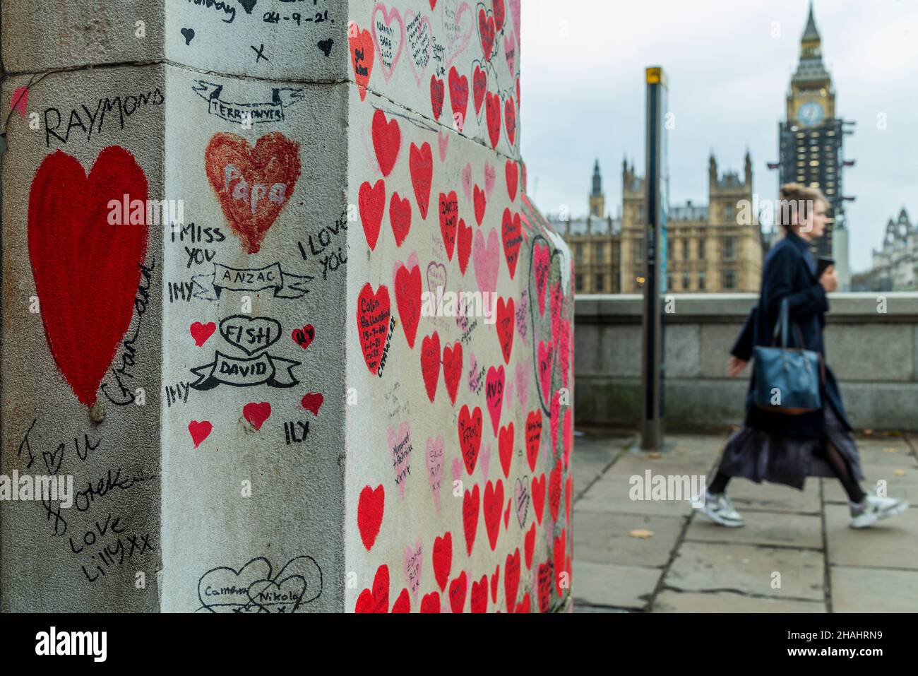 Londra, Regno Unito. 13th Dic 2021. L'arte della gente ancora sta venendo a vedere i cuori sul muro commemorativo di Covid sull'argine - dietro esso le code enormi aspettano pazientemente all'ospedale St Thomas per le vaccinazioni di richiamo di walk-in (terzo) contro Covid 19. Credit: Guy Bell/Alamy Live News Foto Stock