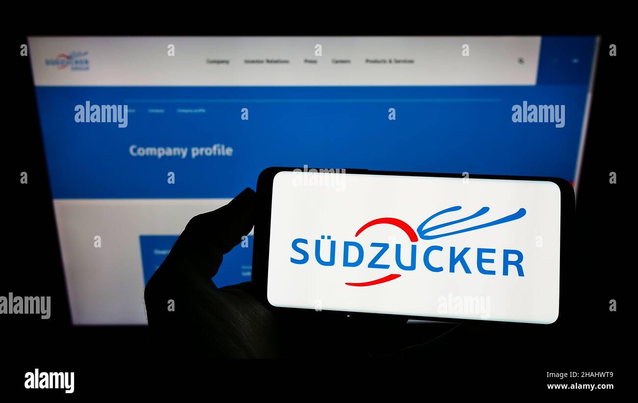 Persona che tiene sullo schermo uno smartphone con il logo della società tedesca di produzione di zucchero Südzucker AG davanti al sito Web. Mettere a fuoco sul display del telefono. Foto Stock