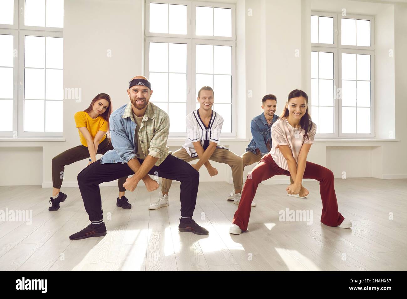 Gruppo di giovani ballerini felici e sorridenti che provano una nuova danza nel loro studio moderno Foto Stock