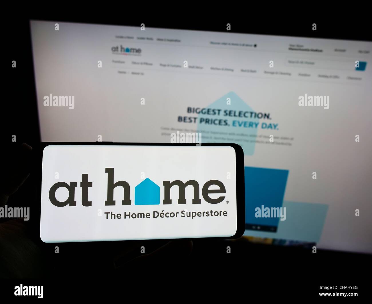 Persona che tiene uno smartphone con il logo dell'azienda di arredamento degli Stati Uniti a Home Group Inc. Sullo schermo di fronte al sito Web. Mettere a fuoco sul display del telefono. Foto Stock