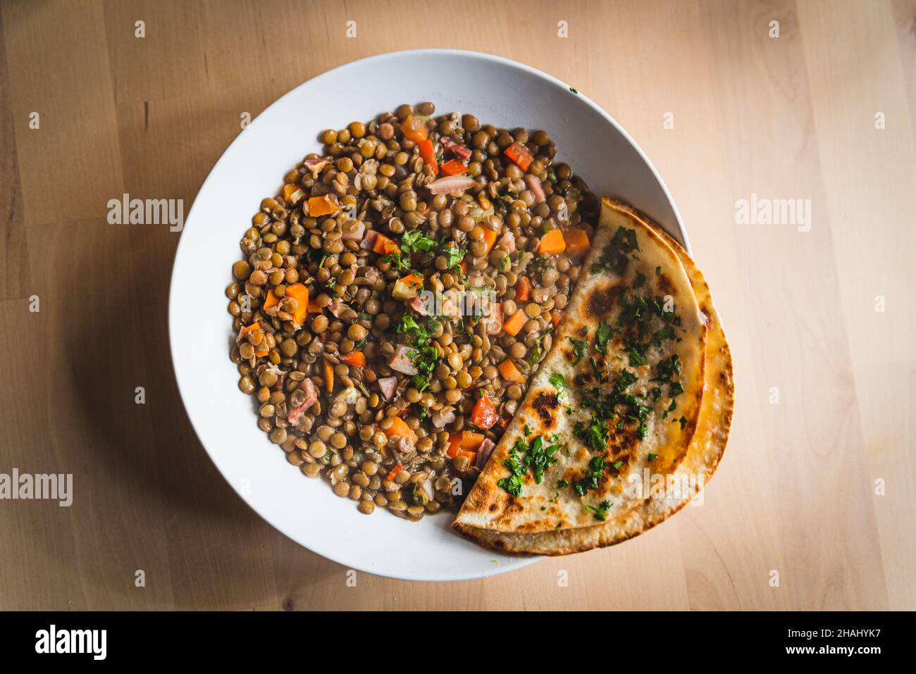 lenticchie vegane fatte in casa con verdure e carote e affumicato, con un pane indiano di roti sul lato con foglie di prezzemolo. luce naturale Foto Stock