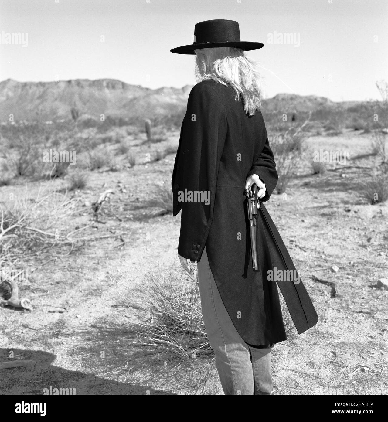 Immagine di stock di una bionda gunfighter femmina in 1860's outfit nel deserto. Foto Stock