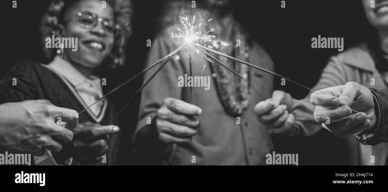 Amici multirazziali divertirsi a festeggiare con fuochi d'artificio - Focus sulla mano destra tenendo scintilla Foto Stock