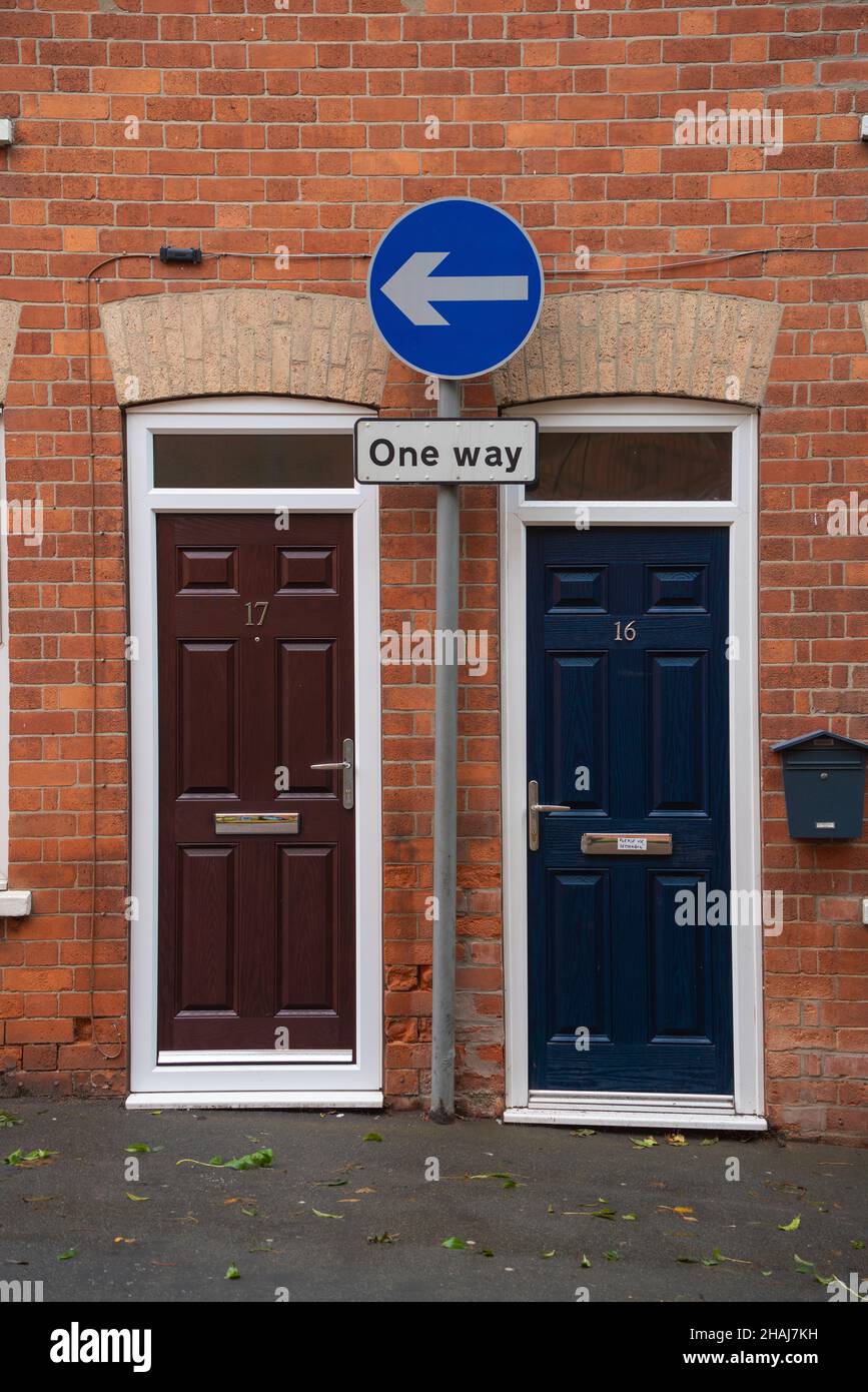 Strada a senso unico, due porte, porte anteriori, 16/17, freccia a senso unico, sentiero, porta marrone, porta blu, edificio in mattoni, scatole di lettere, segnale tra due porte. Foto Stock