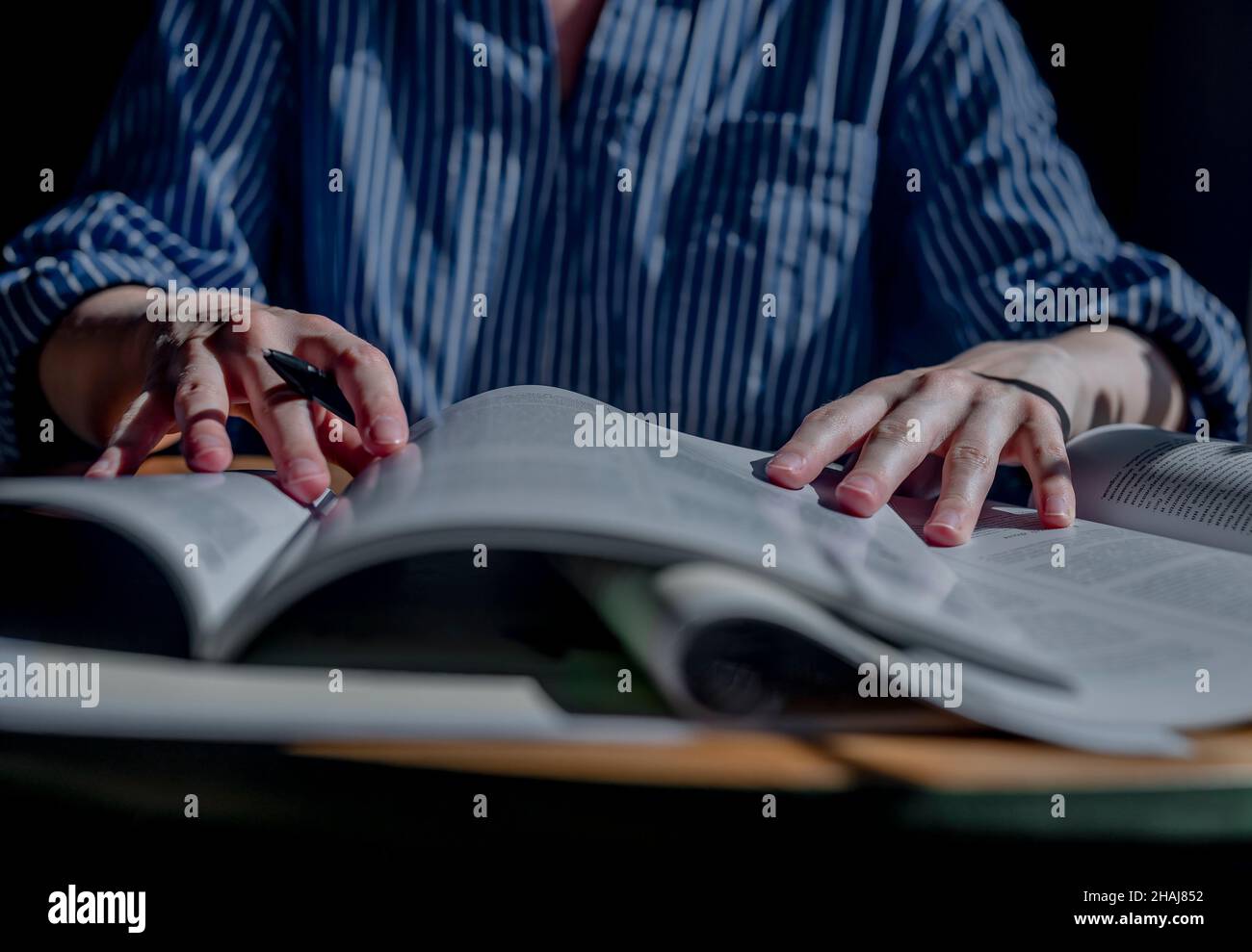 Minsk, Bielorussia - Ottobre 30 2021 lo studente ha le mani in primo piano tenendo la penna e leggendo molti libri. Concetto di ricerca e ricerca di risposte nei libri di testo e nella letteratura accademica. Foto Stock