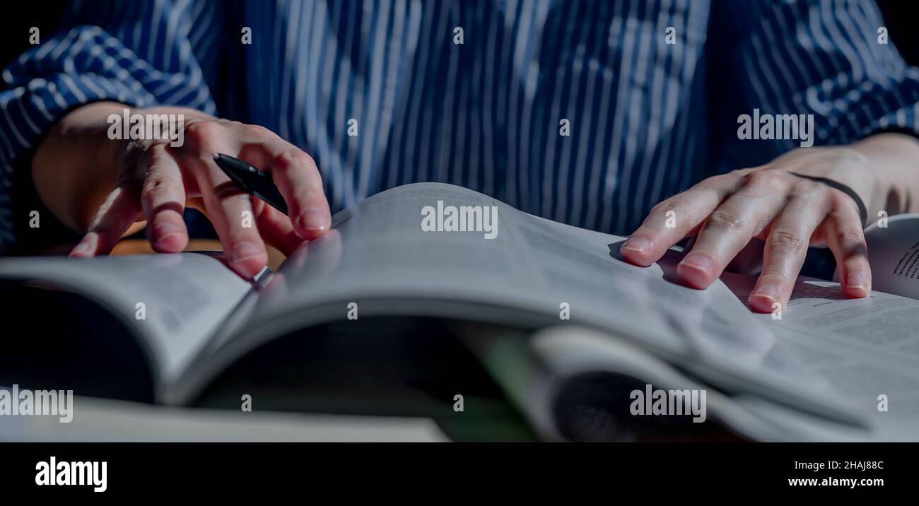 Le mani femminili si chiudono tenendo la penna e leggendo molti libri. Concetto di istruzione. Banner orizzontale. Foto Stock