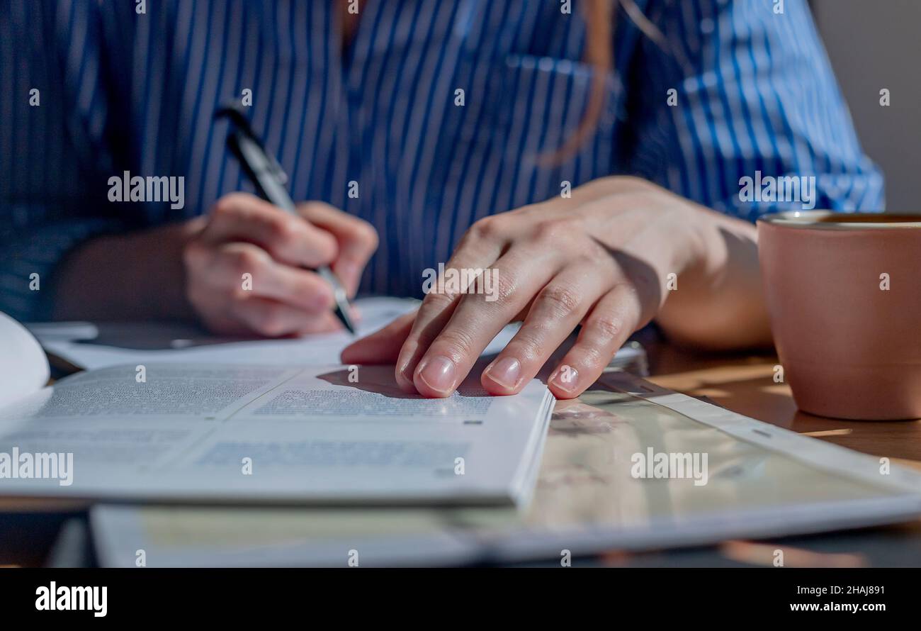 Libri e taccuini su una scrivania in legno nella caffetteria o nella biblioteca. Concetto di ricerca e ricerca di risposte nei libri di testo. Foto Stock