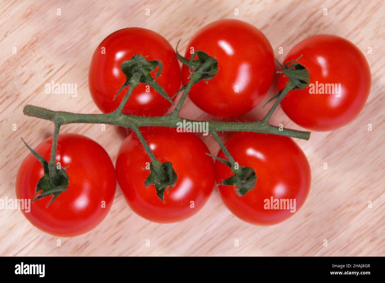 sei pomodori sulla vite su un tagliere di legno Foto Stock