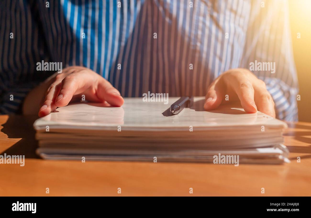 Primo piano delle mani delle donne con la pila di documenti cartacei sulla scrivania in legno. Foto Stock