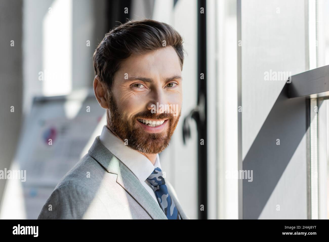 Ritratto di uomo d'affari in abito sorridente alla macchina fotografica in ufficio Foto Stock