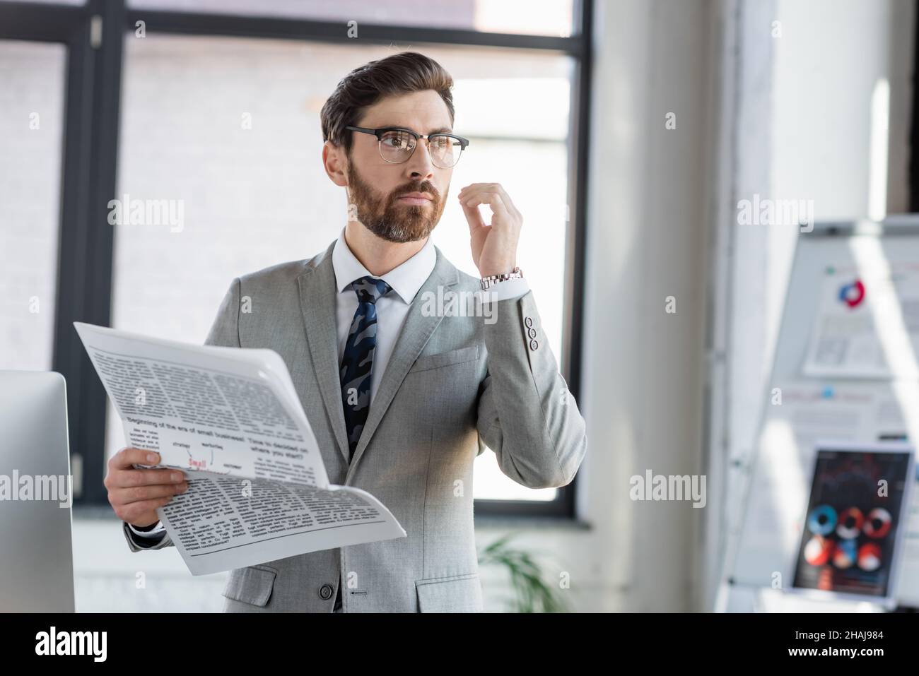 Uomo d'affari in occhiali che tiene il giornale in ufficio Foto Stock