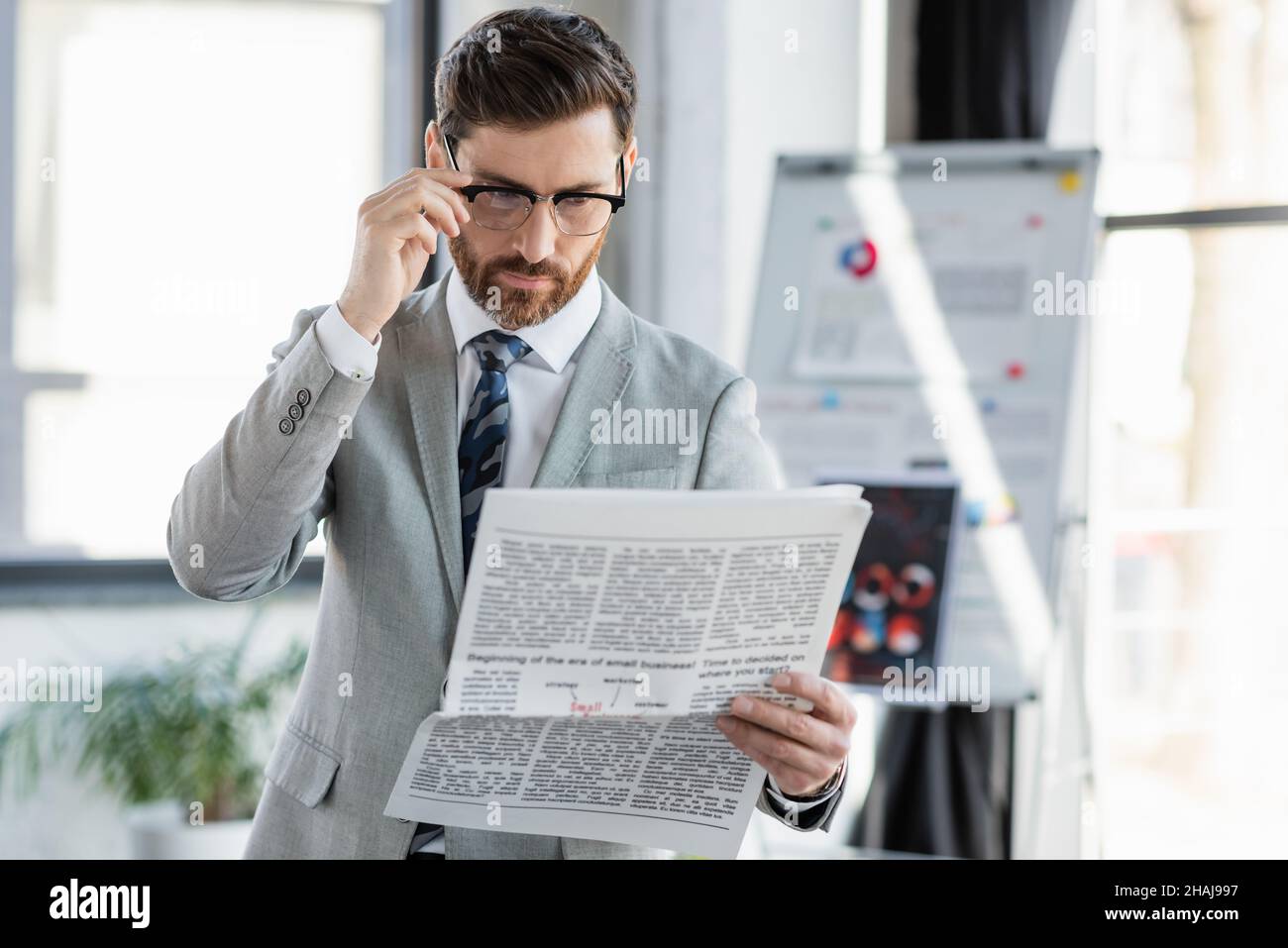Uomo d'affari in occhiali e vestito lettura giornale in ufficio Foto Stock