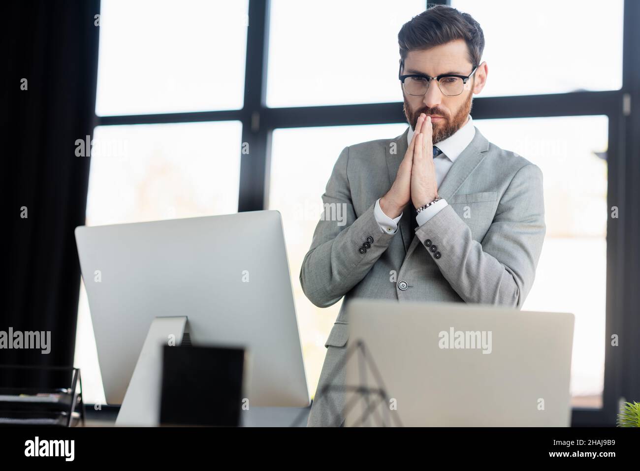 Uomo d'affari concentrato che guarda i computer in ufficio Foto Stock