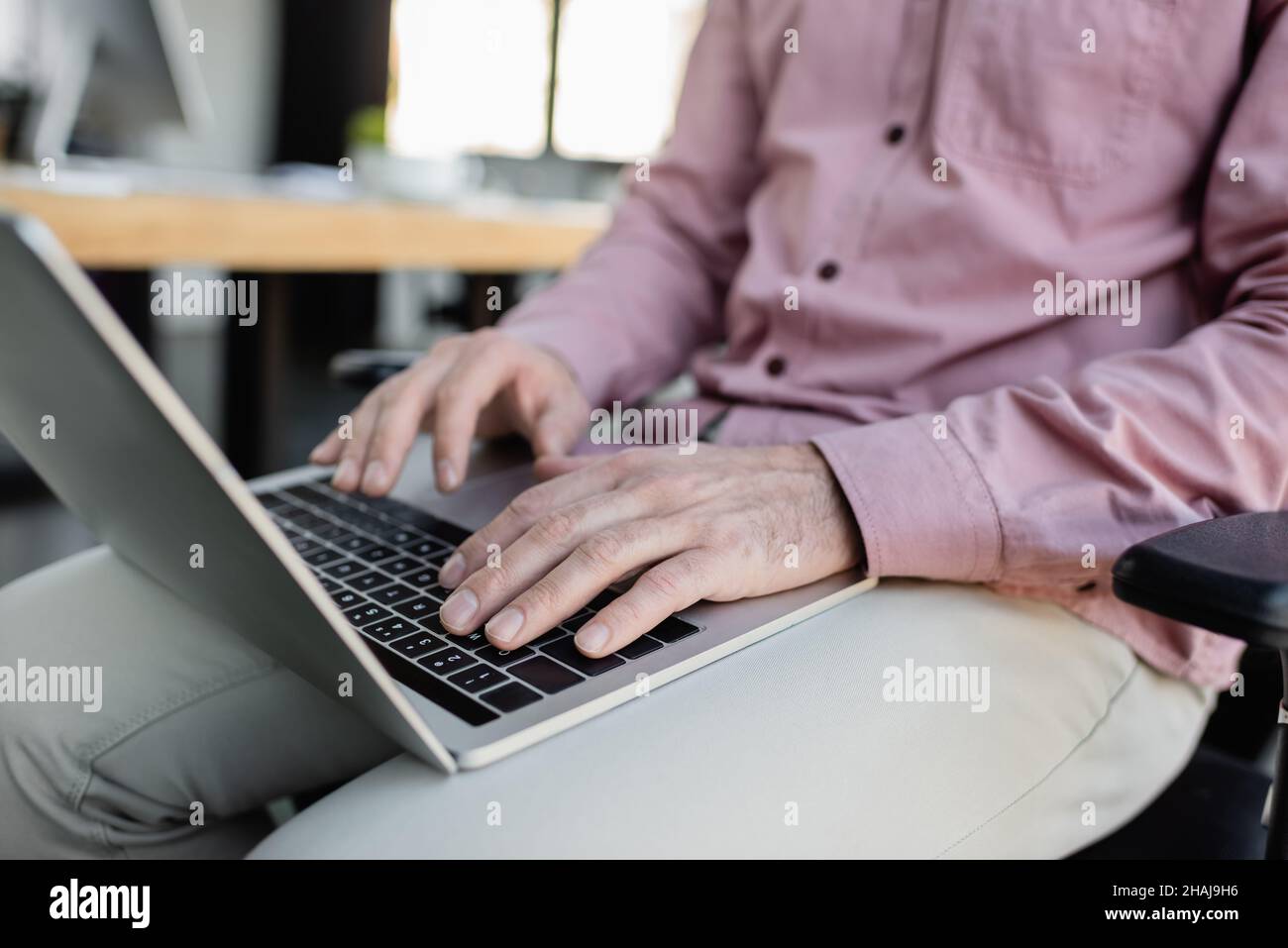 Vista ritagliata di un uomo d'affari che usa un laptop in ufficio Foto Stock