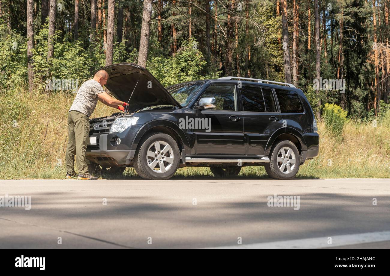 MINSK, BIELORUSSIA - Ottobre 30 2021 conducente in piedi e guardando all'interno del cofano con problemi dopo la pausa auto nel viaggio estivo. Foto Stock