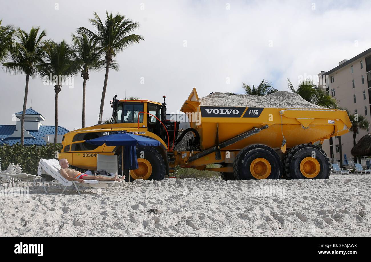 Napoli, Napoli, Stati Uniti. 13th Dic 2021. Un'abbronzatura sulla spiaggia di Vanderbilt a Napoli, Florida, guarda come un trasportatore articolato Volvo A45G passa vicino con un carico di sabbia dalla miniera di Stewart come parte di un progetto di $5 milioni di Beach Renourishment a Napoli Beach. Questa seconda parte del progetto copre circa 1,3 miglia di Vanderbilt Beach dove la contea prevede di trasportare 118.000 tonnellate di sabbia a Vanderbilt perché più sabbia hasÂ eroso lì. (Credit Image: © Bob Karp/ZUMA Press Wire) Foto Stock