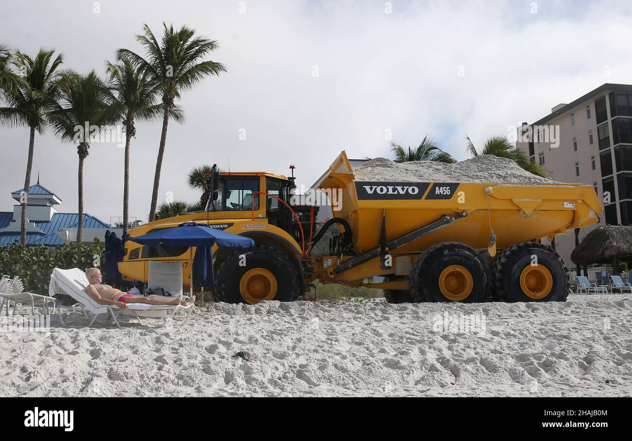 Napoli, Napoli, Stati Uniti. 13th Dic 2021. Un'abbronzatura sulla spiaggia di Vanderbilt a Napoli, Florida, guarda come un trasportatore articolato Volvo A45G passa vicino con un carico di sabbia dalla miniera di Stewart come parte di un progetto di $5 milioni di Beach Renourishment a Napoli Beach. Questa seconda parte del progetto copre circa 1,3 miglia di Vanderbilt Beach dove la contea prevede di trasportare 118.000 tonnellate di sabbia a Vanderbilt perché più sabbia hasÂ eroso lì. (Credit Image: © Bob Karp/ZUMA Press Wire) Foto Stock