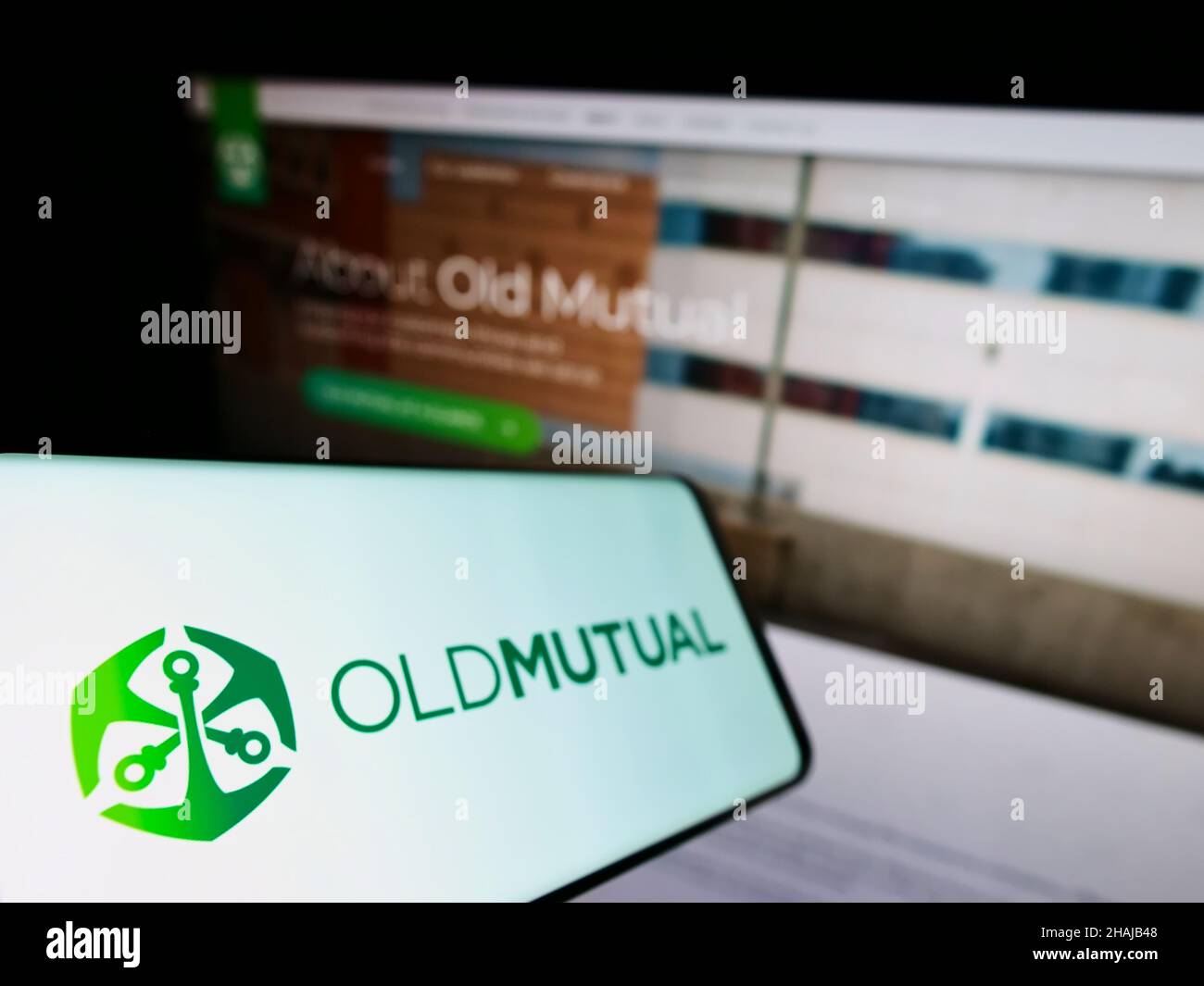 Telefono cellulare con logo della società finanziaria africana Old Mutual Limited (OML) sullo schermo di fronte al sito web. Mettere a fuoco sulla sinistra del display del telefono. Foto Stock