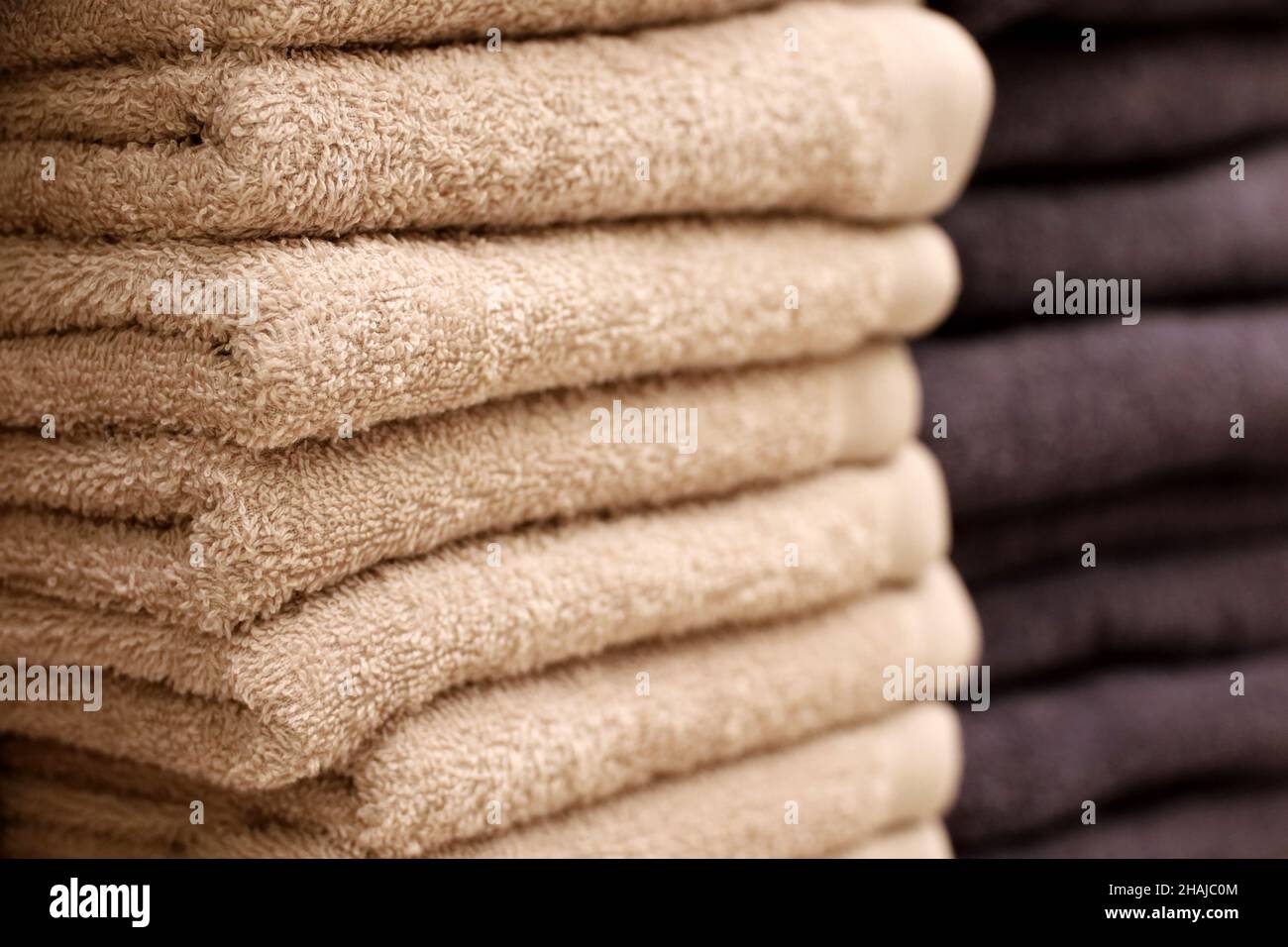 Pila di asciugamani di spugna, fuoco selettivo. Panno da bagno beige e scuro in primo piano Foto Stock