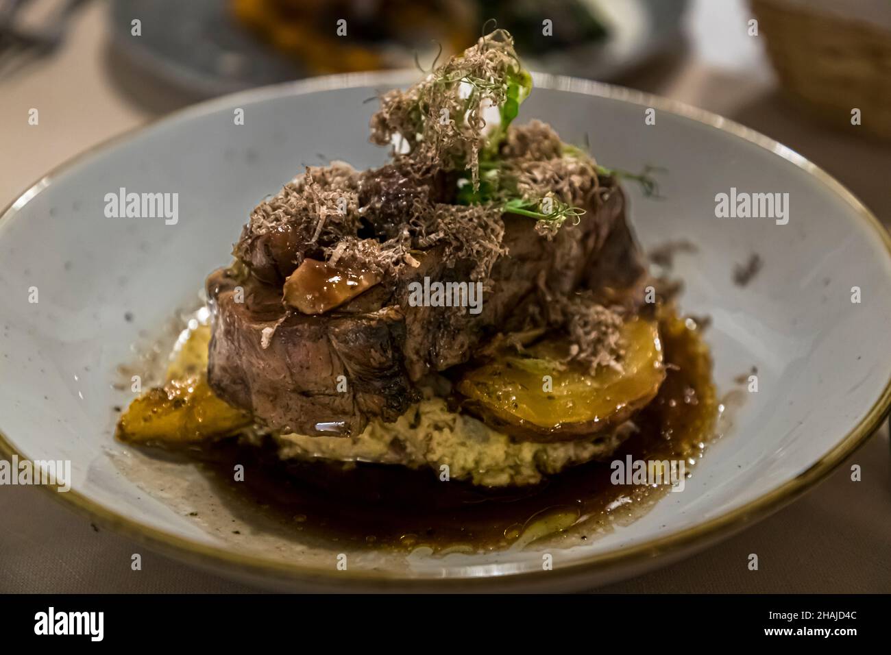 Un piatto di carne brasata con tartufo nero grattugiato e salsa scura poggia su un letto di purè di patate o sedano, servito da Alexandre Dimtch al Restaurant Saint Marc ad Aups, Var, Francia. Foto Stock