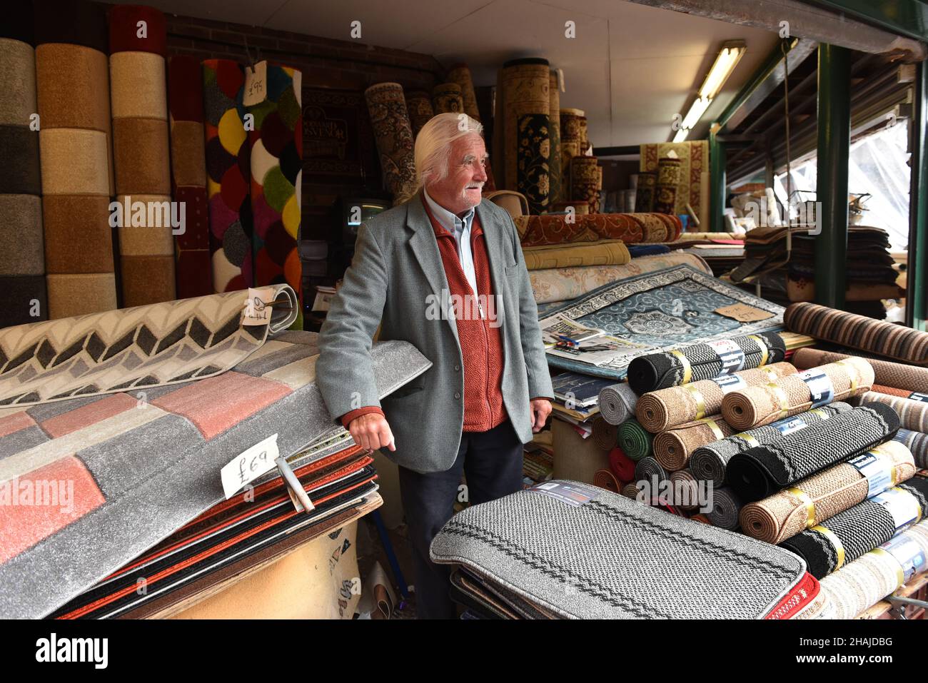 Uomo che vende tappeti sul mercato di stallo Wellington Market , Shropshire, Gran Bretagna, Regno Unito. Market Traders commerciante stallholder stallholder Foto Stock