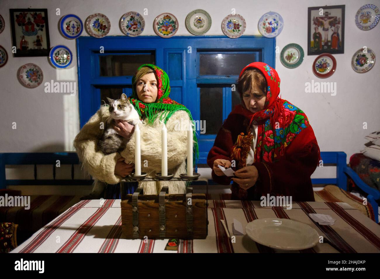 UZHHOROD, UCRAINA - 10 DICEMBRE 2021 - due donne in un costume tradizionale ucraino siedono al tavolo durante la celebrazione di Andriivski Vechornytsi a. Foto Stock