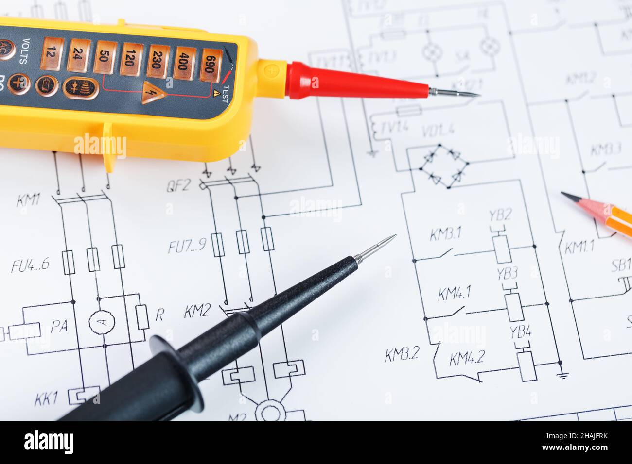 Indicatore di tensione giallo in primo piano sullo schema elettrico. Test e verifica delle reti elettriche Foto Stock